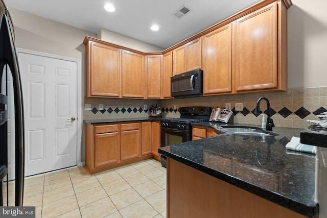 kitchen featuring visible vents, dark stone countertops, black appliances, a sink, and light tile patterned flooring