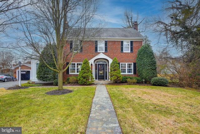 view of front of home featuring a front yard, a chimney, and brick siding