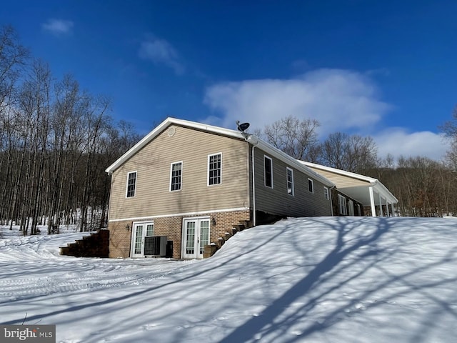 view of snowy exterior featuring cooling unit and french doors