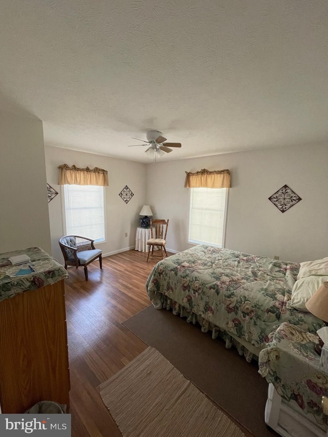 bedroom with ceiling fan, dark hardwood / wood-style floors, and a textured ceiling