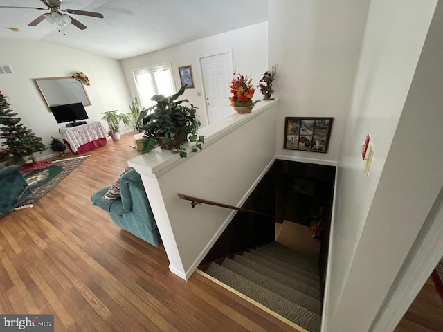 staircase featuring wood-type flooring and ceiling fan