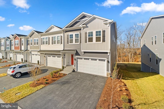 view of property featuring a garage, driveway, board and batten siding, and a residential view