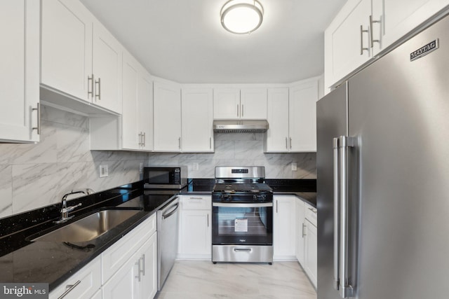 kitchen featuring sink, appliances with stainless steel finishes, white cabinetry, backsplash, and dark stone counters