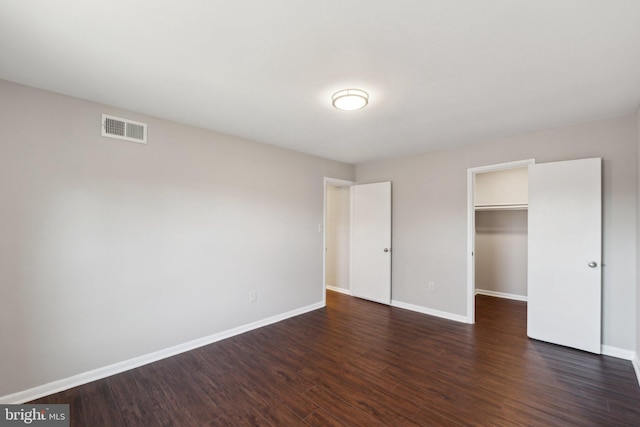 unfurnished bedroom with a walk in closet, dark hardwood / wood-style flooring, and a closet