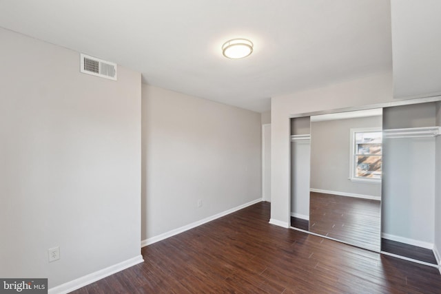 unfurnished bedroom with dark hardwood / wood-style flooring and a closet