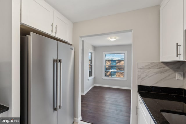 kitchen with backsplash, dark stone countertops, high end fridge, and white cabinets