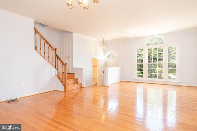 unfurnished living room featuring an inviting chandelier, crown molding, and light hardwood / wood-style flooring