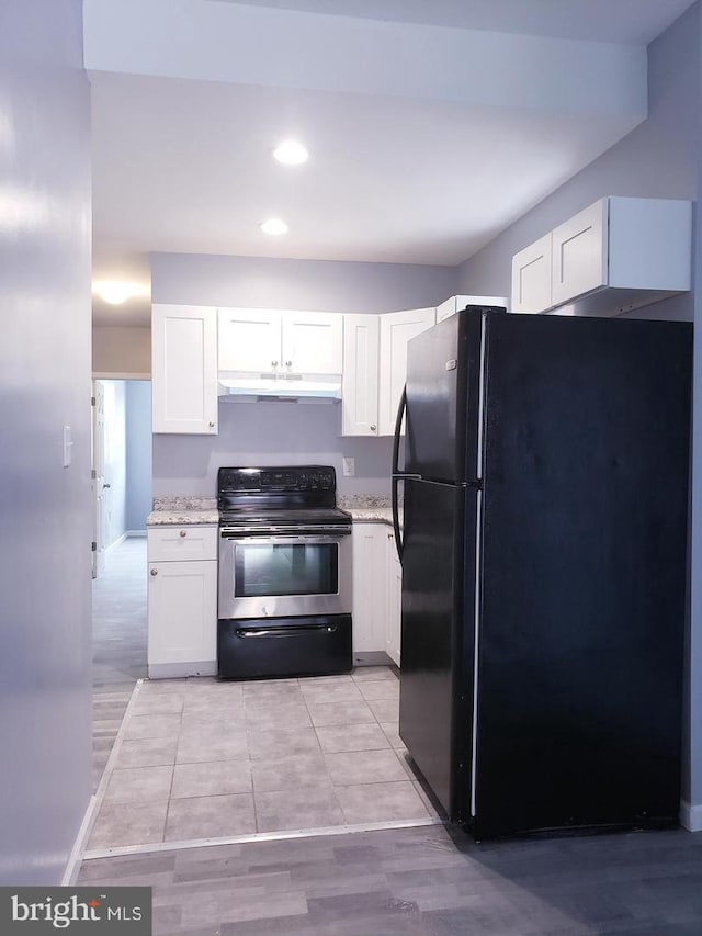 kitchen with black fridge, white cabinetry, light stone counters, and electric range