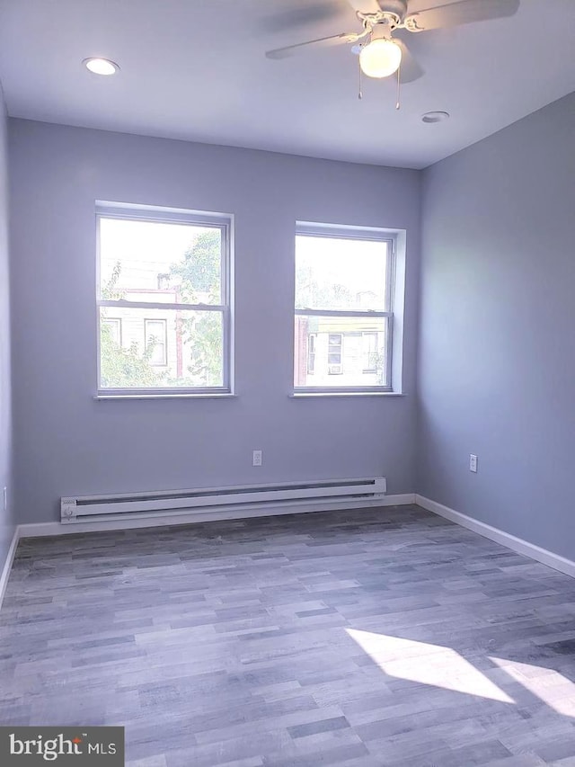 unfurnished room featuring hardwood / wood-style flooring, ceiling fan, and baseboard heating