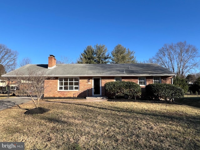 view of front of home with brick siding, a chimney, and a front lawn