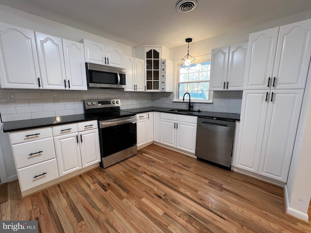 kitchen featuring visible vents, glass insert cabinets, appliances with stainless steel finishes, white cabinetry, and a sink