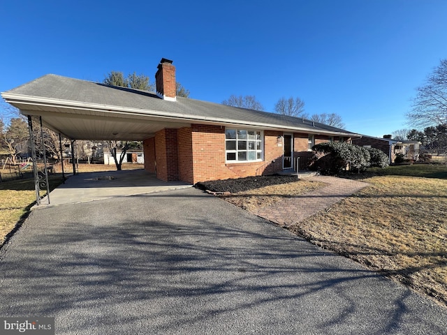 ranch-style home featuring driveway, a chimney, a carport, and brick siding