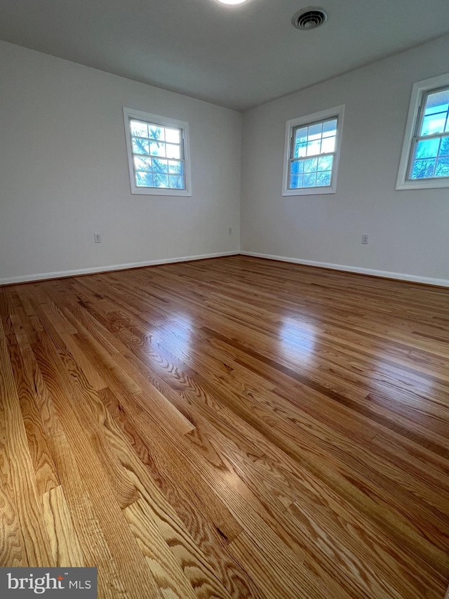 empty room featuring light wood-type flooring, visible vents, and baseboards