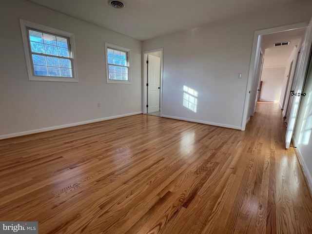 empty room featuring light wood-style flooring, visible vents, and baseboards