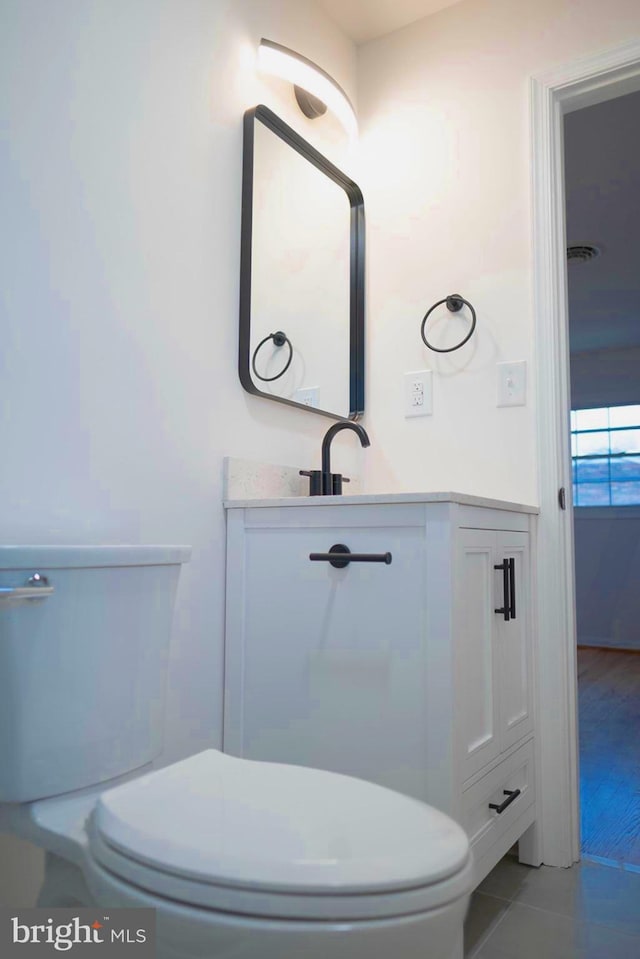 bathroom with toilet, tile patterned flooring, and vanity