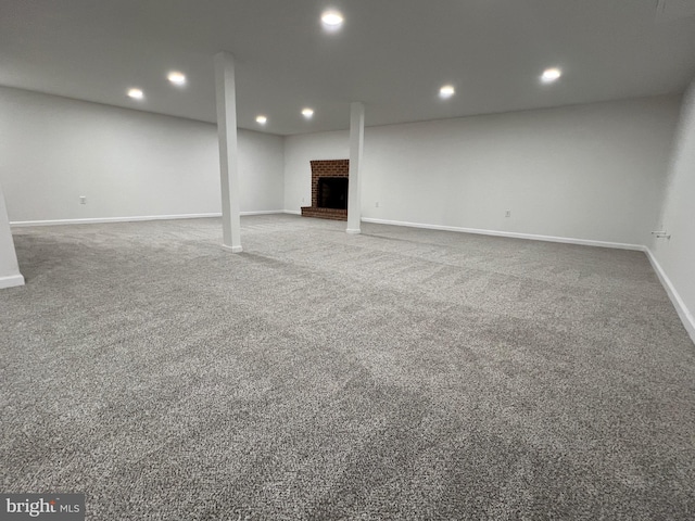 finished below grade area with baseboards, a brick fireplace, carpet flooring, and recessed lighting