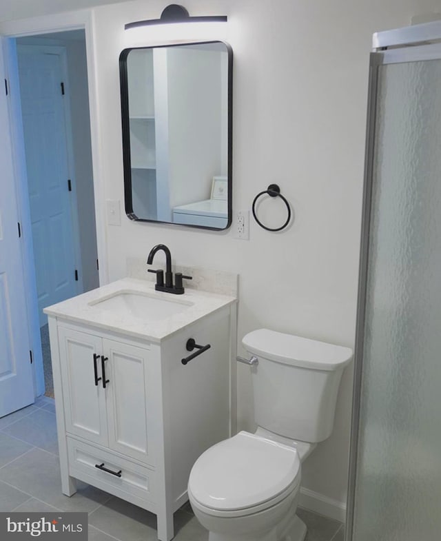 bathroom with toilet, baseboards, vanity, and tile patterned floors