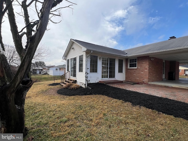 view of side of home with a patio and a lawn