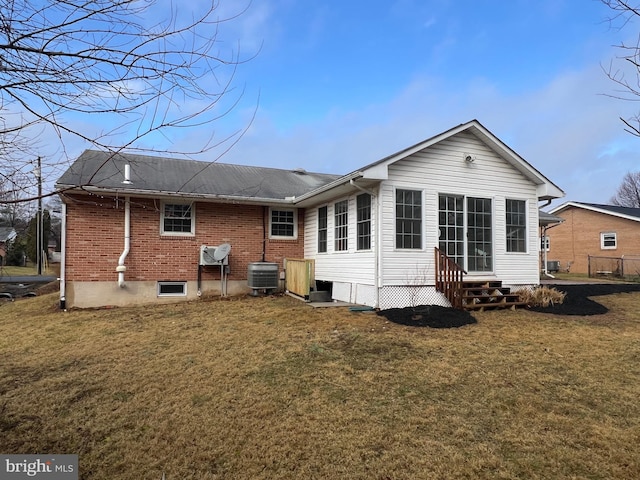 back of property featuring entry steps, brick siding, a yard, and central air condition unit