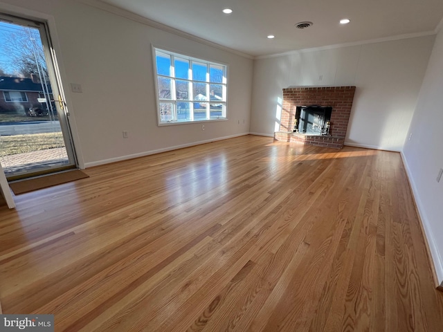 unfurnished living room featuring light wood-style floors, a fireplace, crown molding, and baseboards