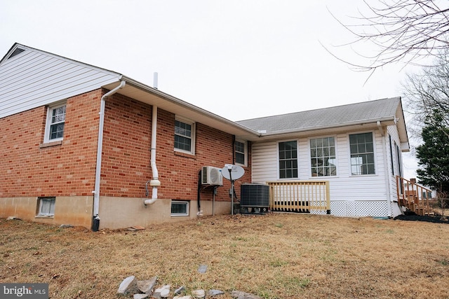 view of property exterior with brick siding, cooling unit, and a yard