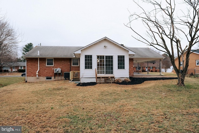 rear view of house featuring entry steps, brick siding, a lawn, and central AC unit