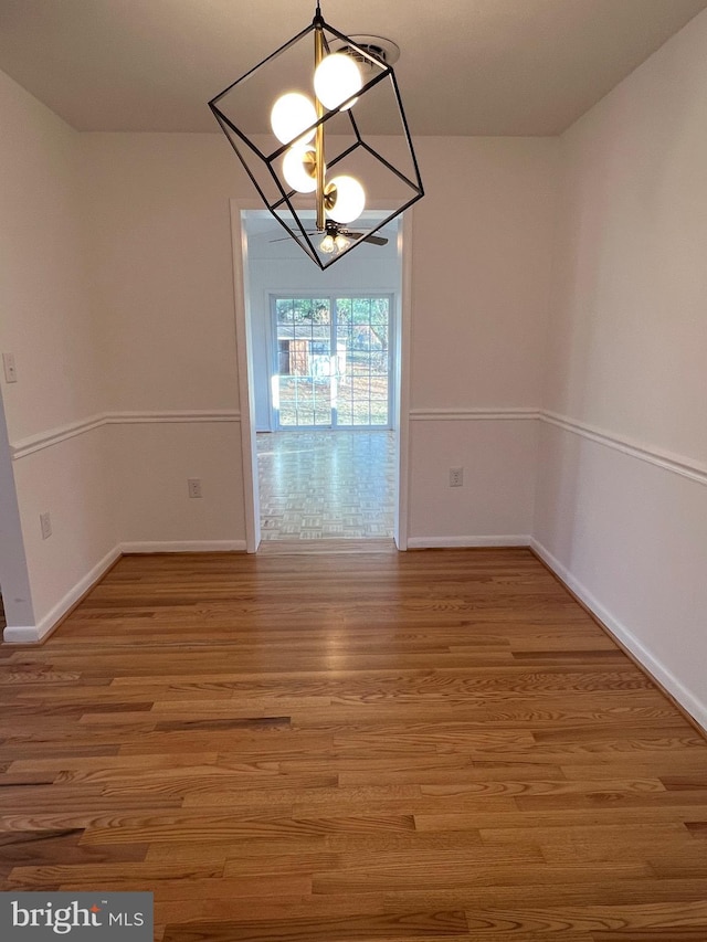 unfurnished dining area with hardwood / wood-style flooring and a notable chandelier