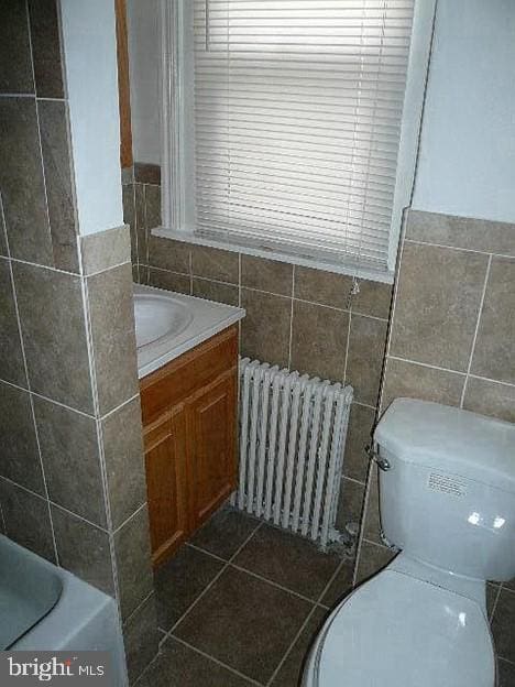 bathroom featuring radiator, tile walls, vanity, toilet, and tile patterned floors