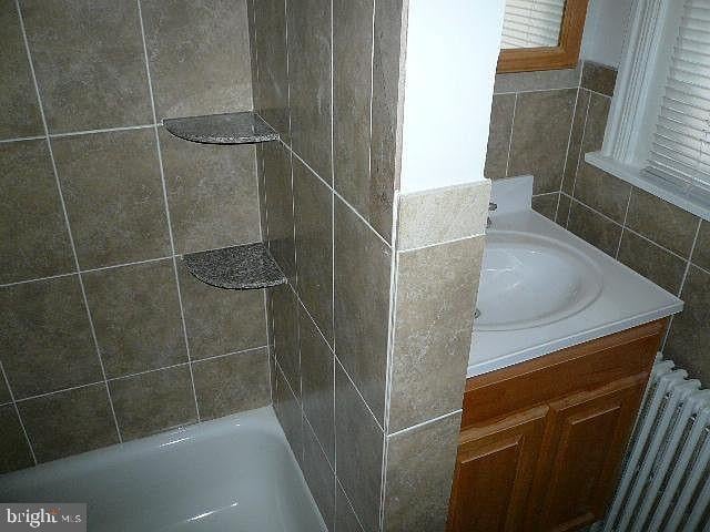 bathroom with vanity, radiator, and a bathing tub