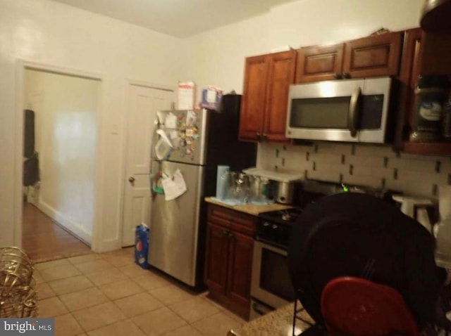 kitchen featuring stainless steel appliances, tasteful backsplash, and light tile patterned floors