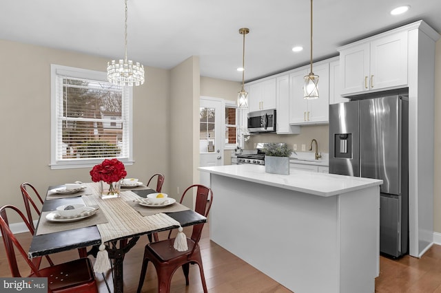 kitchen featuring stainless steel appliances, a center island, hanging light fixtures, and white cabinets