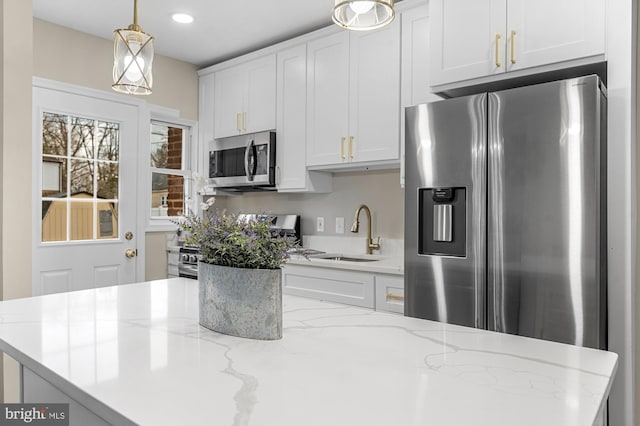 kitchen with white cabinetry, appliances with stainless steel finishes, sink, and hanging light fixtures