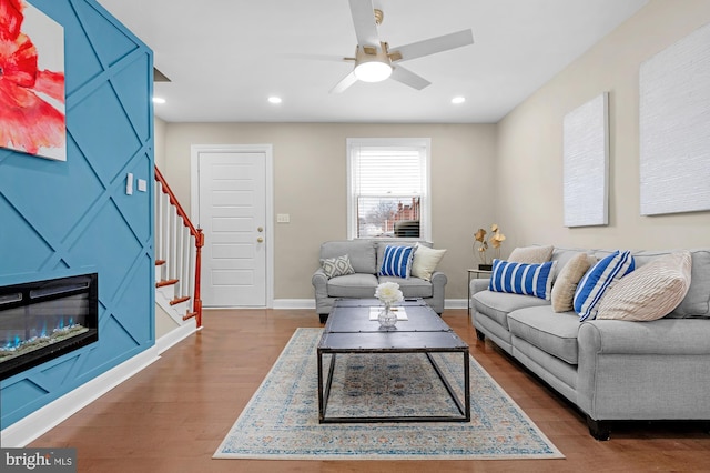 living room with ceiling fan, a large fireplace, and hardwood / wood-style floors