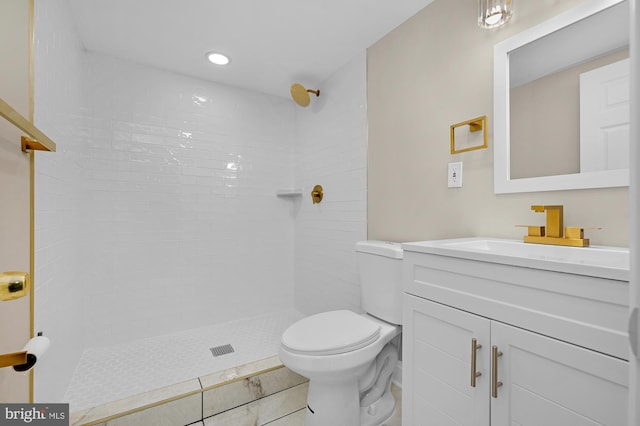 bathroom with vanity, toilet, and a tile shower