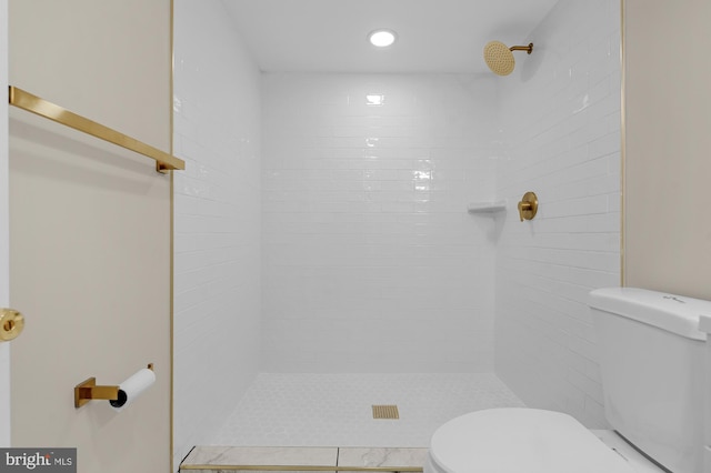 bathroom with a tile shower and toilet