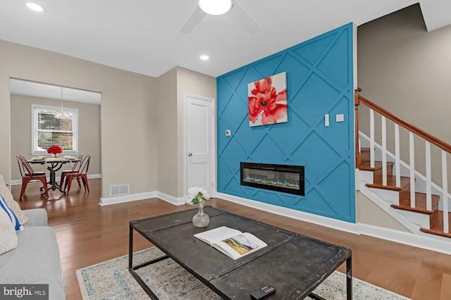 living room featuring wood-type flooring, ceiling fan, and a fireplace