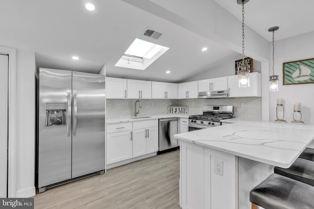 kitchen featuring white cabinetry, appliances with stainless steel finishes, a breakfast bar, and kitchen peninsula