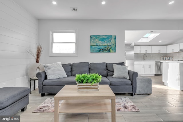 living room with sink, a skylight, and light wood-type flooring