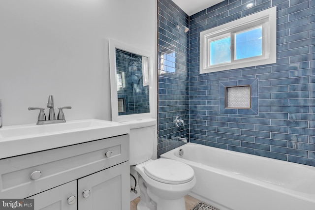 full bathroom featuring tiled shower / bath, vanity, and toilet