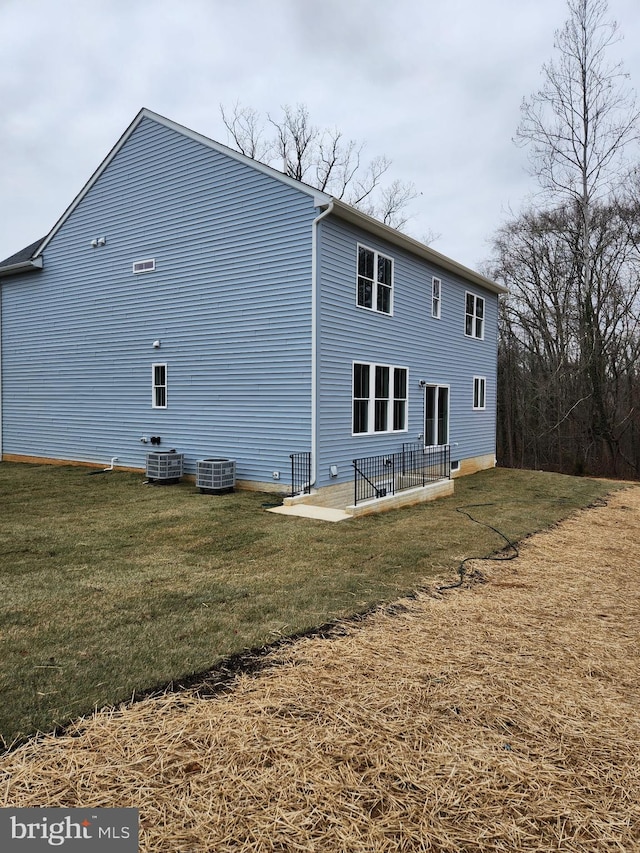 back of house featuring cooling unit, a yard, and a patio