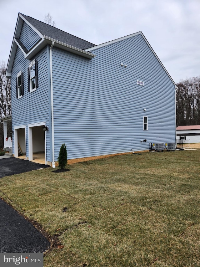 view of property exterior with cooling unit, a garage, and a yard