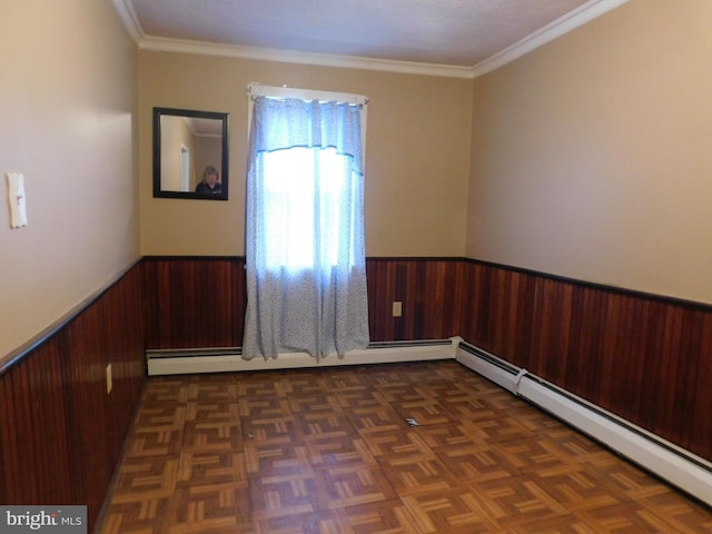 unfurnished room with ornamental molding, baseboard heating, wainscoting, and wooden walls