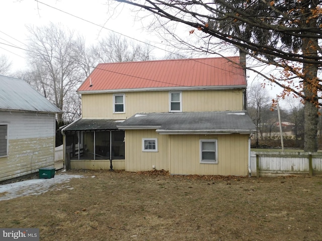 rear view of house featuring a sunroom, fence, metal roof, and a yard