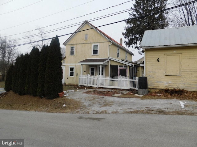 view of front of property with metal roof and fence