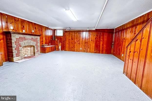 unfurnished living room featuring a brick fireplace and wood walls