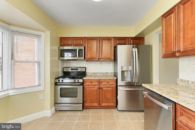 kitchen with light tile patterned flooring, appliances with stainless steel finishes, and light stone counters