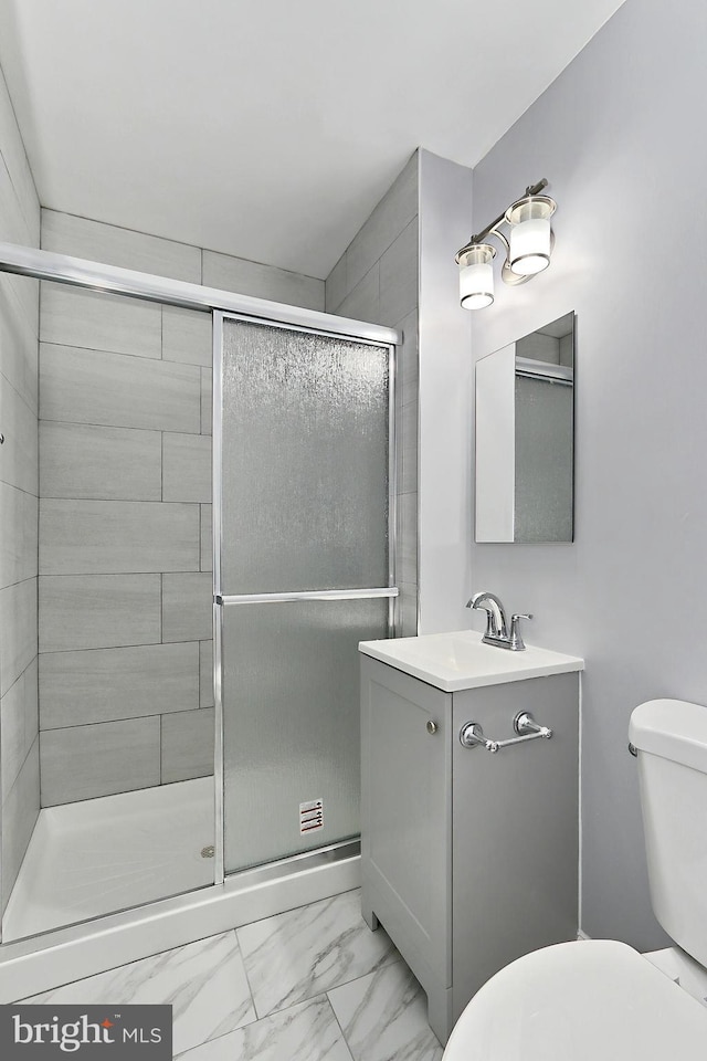 bathroom with vanity, a shower with door, and toilet