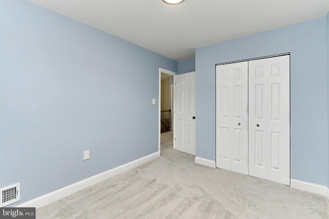 unfurnished bedroom with light carpet and a closet