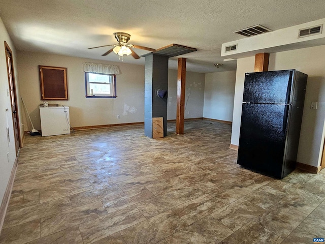 kitchen featuring black fridge, ceiling fan, washer / dryer, and a textured ceiling