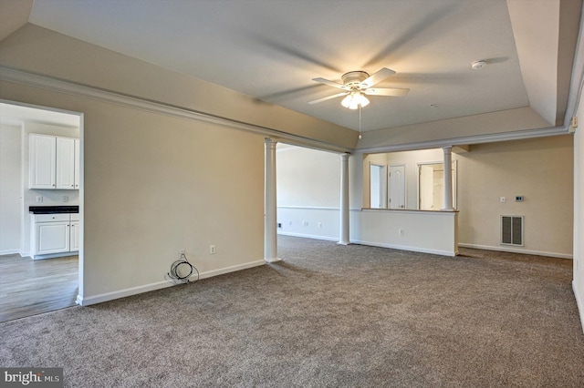 unfurnished living room with ceiling fan, carpet flooring, and ornate columns